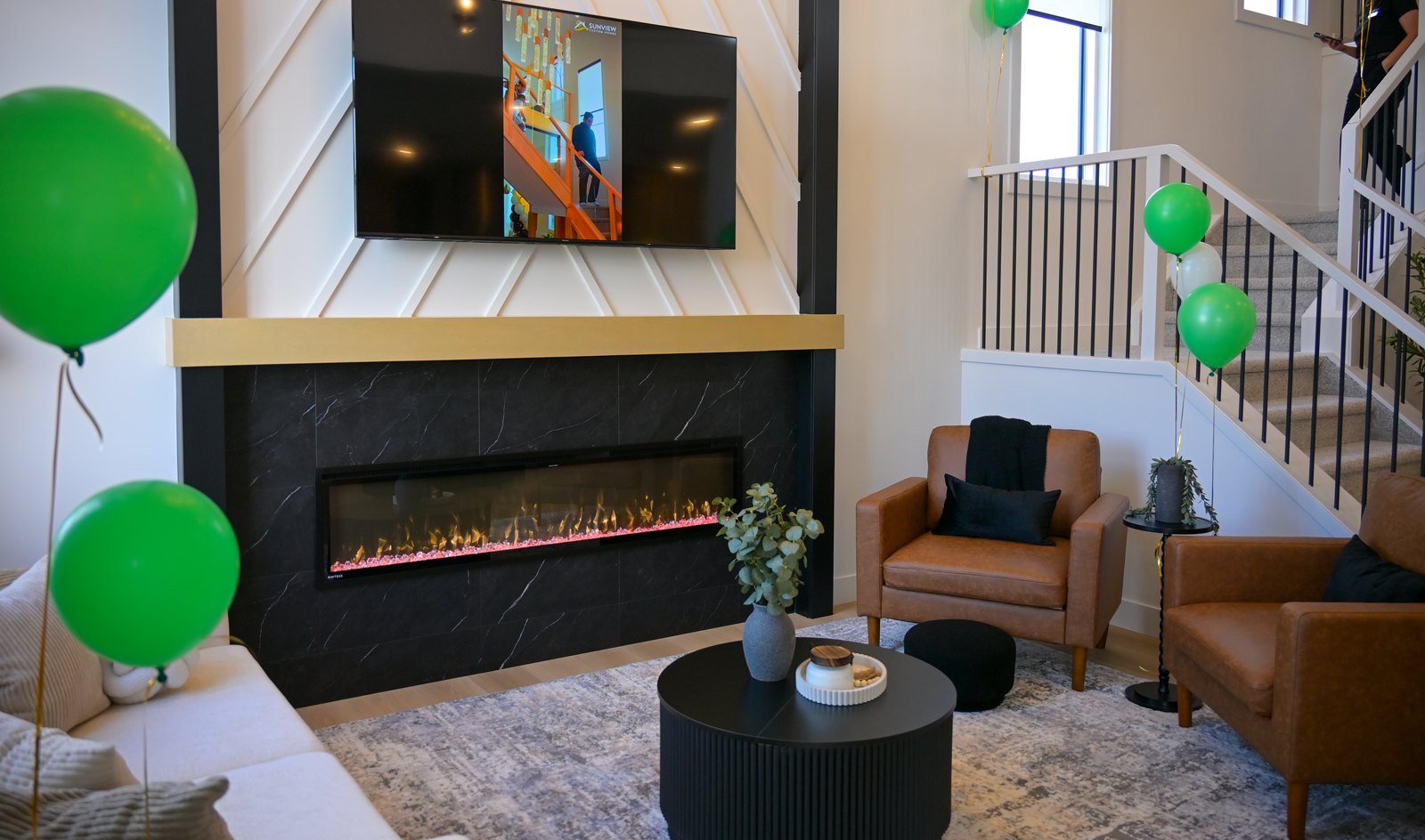 Great room with linear fireplace and green and white balloons
