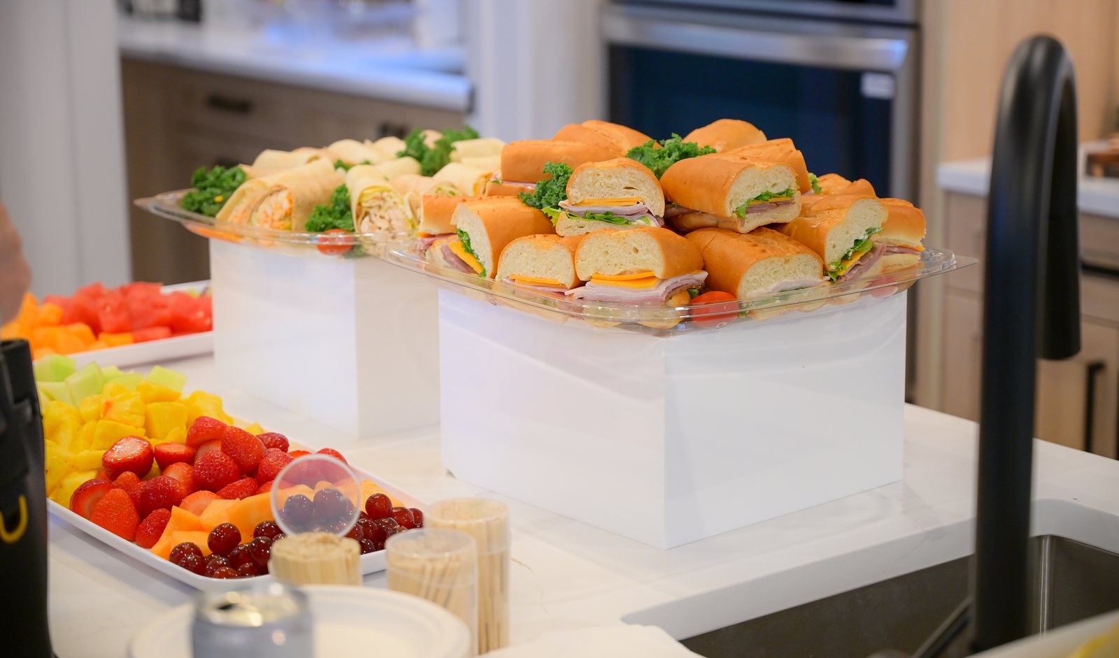 Sandwiches and fruit platters on the kitchen island in the Aspen Living showhome