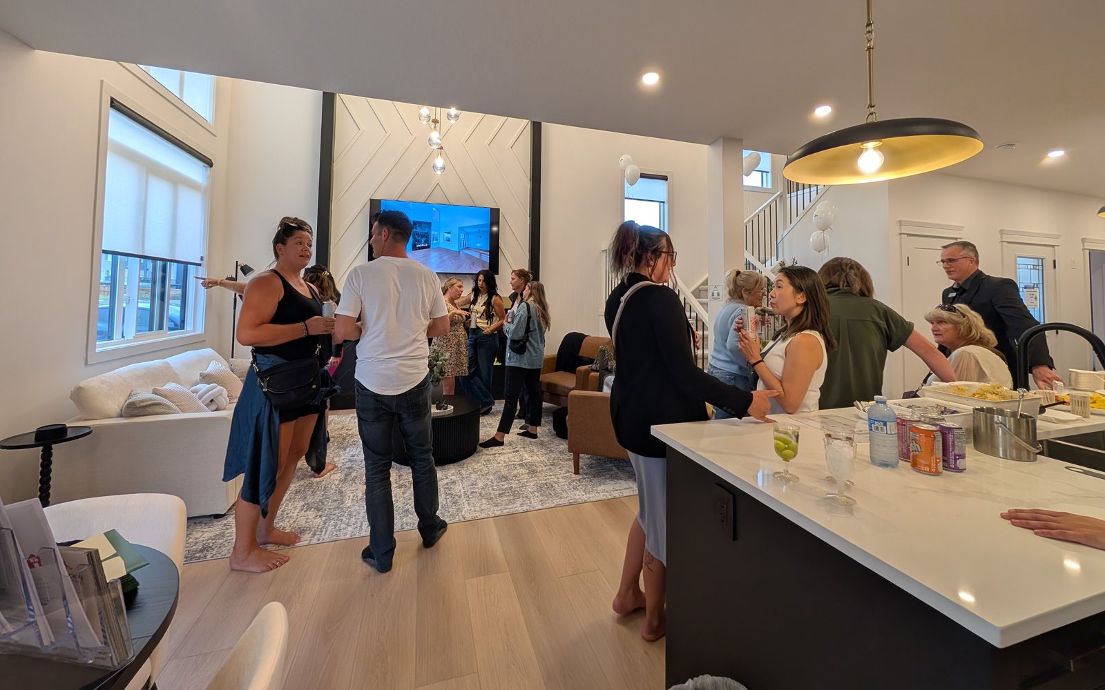 Realtors mingling in the great room and kitchen of the Aspen Living showhome in Edgefield, Strathmore, during the August 2026 preview night