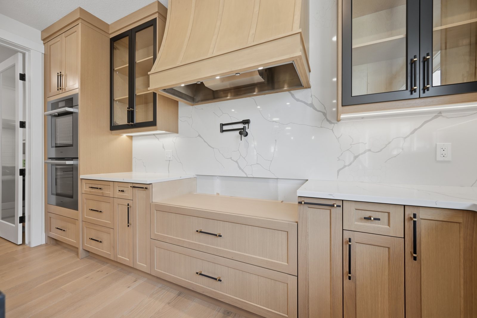 Kitchen with wood cabinets and a range hood in a Waterford Estates home by Aspen Living